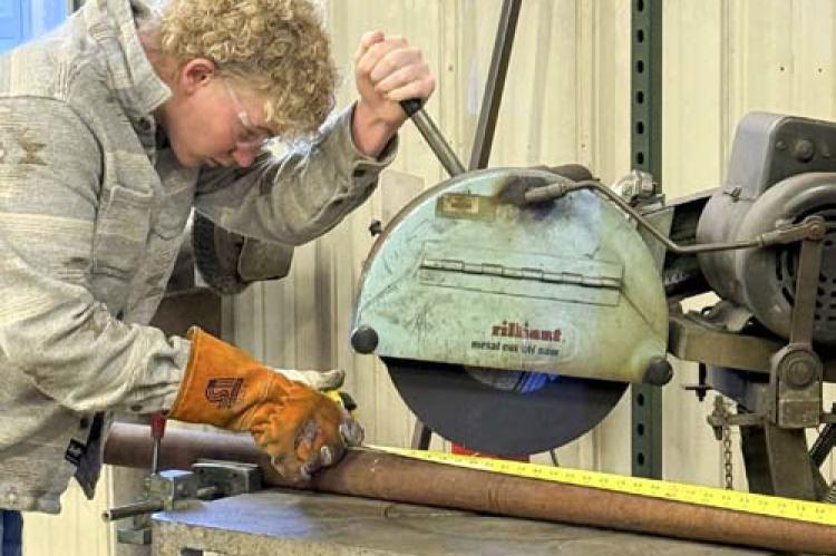 Sophomore Bo Kyler cuts pipe with a chop saw in the agriculture fabrication class. Ag fab is the advanced welding class.