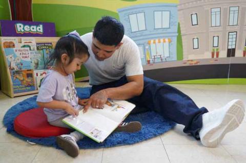 A resident reads with his daughter in the newly completed visitation area at the Ellsworth Correctional Facility. Courtesy photo